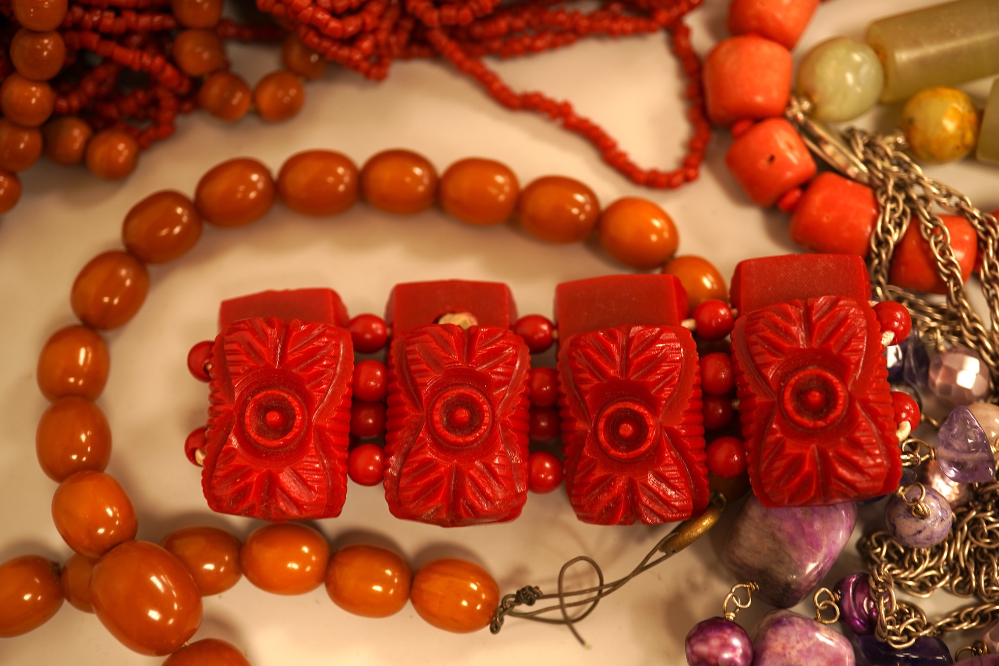 A small group of sundry jewellery including a simulated amber necklace and a multi strand coral bead necklace, etc.